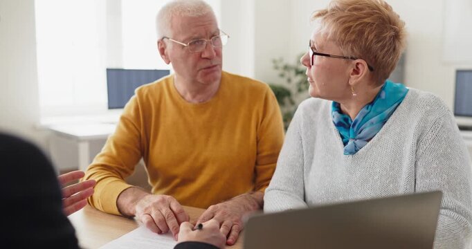 Senior couple with advisor reviewing contract signing. Expert consultation in a bright office covers financial options and paperwork for loans or property. Clear trust and guidance theme.