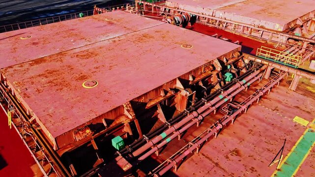 Drone flies above rusty cargo hatch as bulk carrier awaits coal loading