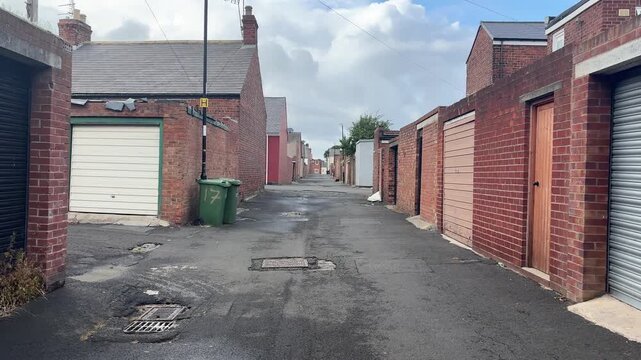 POV walking through a British lower class alleyway between small houses and garages. Sunderland, UK