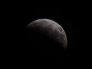 Partial lunar eclipse showing the Earth’s shadow moving across the surface of the Moon against a dark night sky. © Dmytro