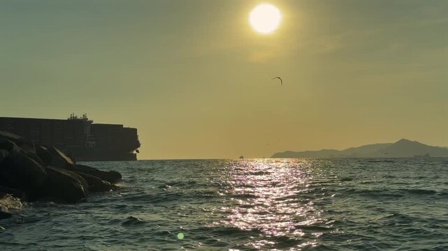 Barco carguero o buque de carga navegando en el mar avanzando saliendo del puerto al atardecer en el horizonte en el océano pacifico medio de transporte maritimo con contenedores sobre el mar