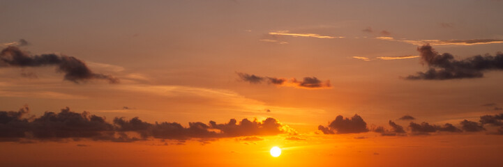 Fototapeta premium Panoramic golden sunset sky background with glowing sun disk and orange clouds