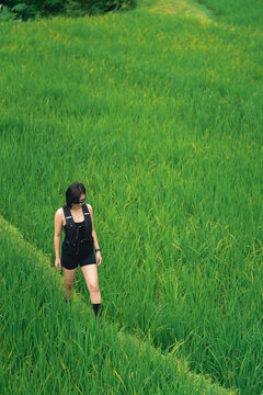 Young woman walking through lush green field in casual summer outfit enjoying nature outdoors during daytime