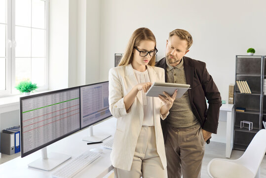 Businesswoman and businessman analyzing tablet data in office. Coworkers review finance and accounting metrics, align budgets, and set reporting targets. Strong concept of teamwork and finance.
