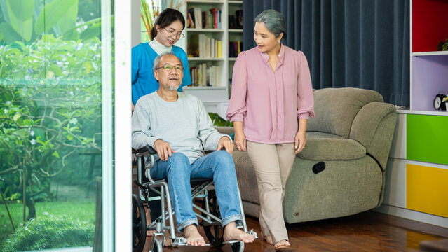 Asian old man on wheelchair with couple and nurse relaxing walking at home, healthcare medical service at nursing home