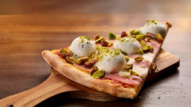 White pizza slice with burrata and pistachios with blurred pizzeria background banner
