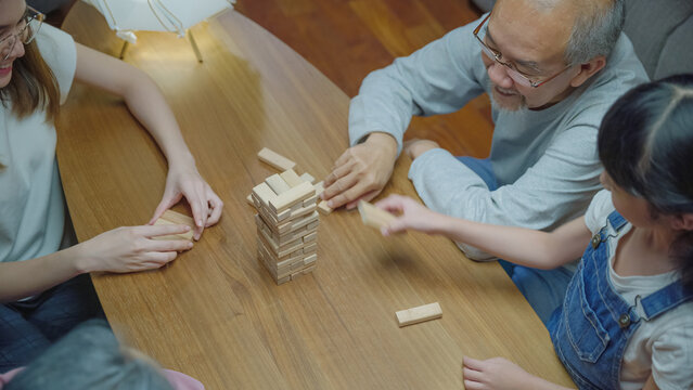 Asian family enjoy playing toy block with little daughter together in home living room