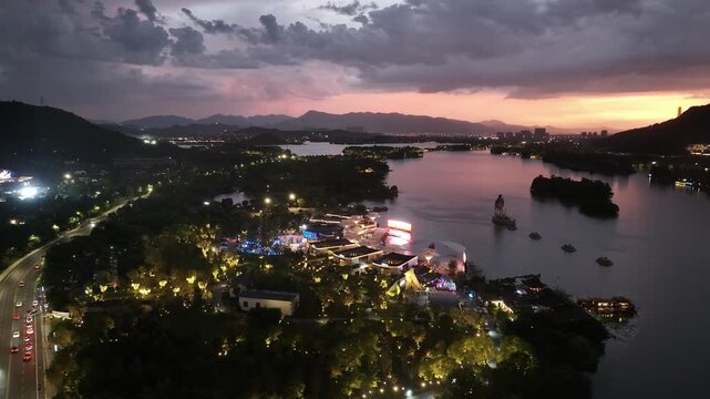 Aerial view of city lake lights at dusk with mountains and roads