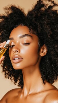 Woman with beautiful coily hair carefully applying golden beauty oil to her radiant face. Her healthy glowing skin highlights natural care and wellness.