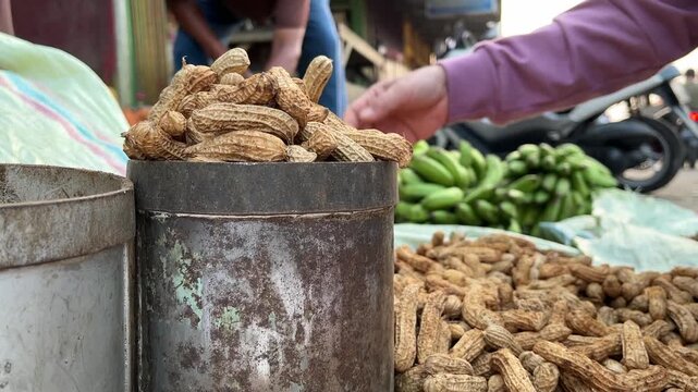Vendor Sorting Raw Peanuts Beside Traditional Metal Measuring Tin
