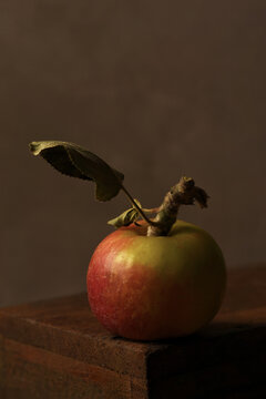 Apple Still Life. A ripe fuji apple on a wooden box, low key lighting