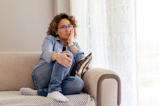 Worried mature woman sitting alone on a couch