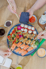 Friends eating a large platter of assorted sushi rolls © Cavan