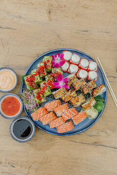 A large mixed sushi platter on a wooden table with sauces