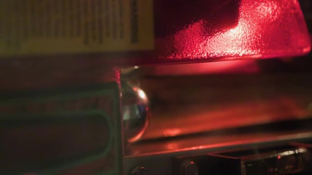 Chrome pinball rolls along a metal shooter lane beneath glowing red arcade light. Moody retro gaming mood with dramatic shadows for entertainment and nostalgia themes.