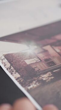 Very close-up shot showing a pen pointing or tracing on a printed sheet with an architectural image on a dark surface
