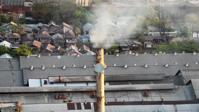 Industrial smoke rising from a factory chimney located near residential houses in Banjarmasin