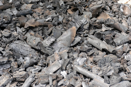 Pile of burned hardwood charcoal pieces showing black gray textures irregular shapes suitable for fuel barbecue cooking traditional charcoal production