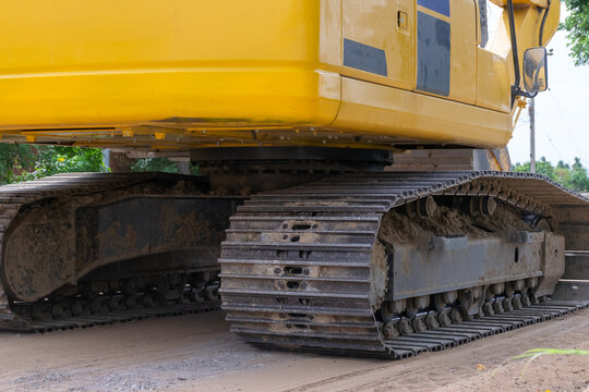Close view of heavy crawler excavator steel tracks undercarriage dirt construction site showing rugged machinery used for earthmoving excavation work