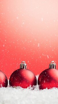 Animation of christmas baubles decorations with snow falling on red background