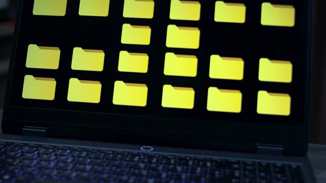 Close-up laptop screen displaying a grid of yellow file folder icons on a dark interface, representing digital file management, data storage, database, document management, and information overload.
