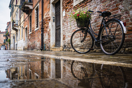 Old European stone alley with bicycle and puddle reflection