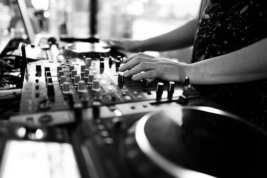 Black and white close-up of DJ hands mixing music on professional equipment