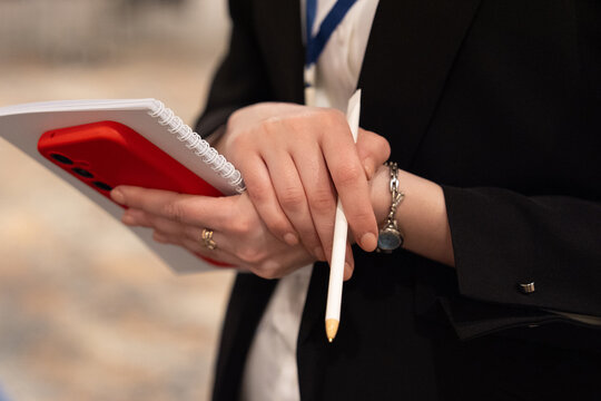Close-up of a person holding a notebook and pen during a professional event