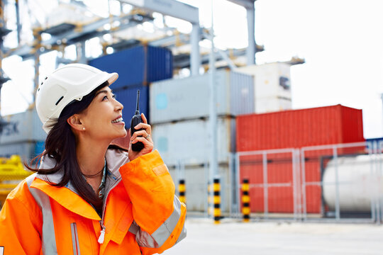 Logistics, discussion or woman on dock with radio, inventory control or site operations in chat. PPE, freight or coordinator in yard with tech, shipment track or dispatch instruction in communication