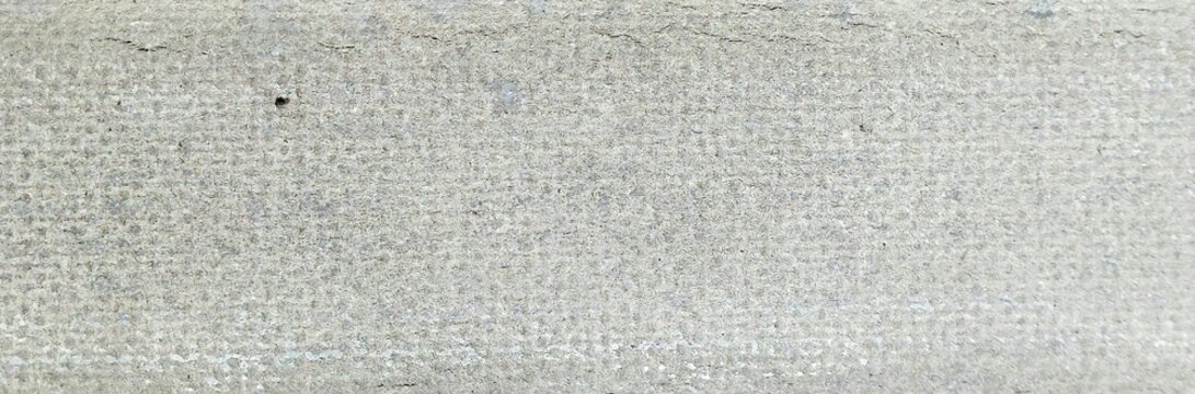 Close-up of gray gypsum board surface texture with fine dot pattern background.