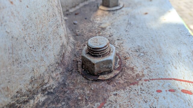 Close-up of a rusty hex bolt fastened on a worn metal surface, showing texture, corrosion, and aging
