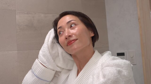 お風呂上がりに濡れている髪をバスタオルで拭く女性　
