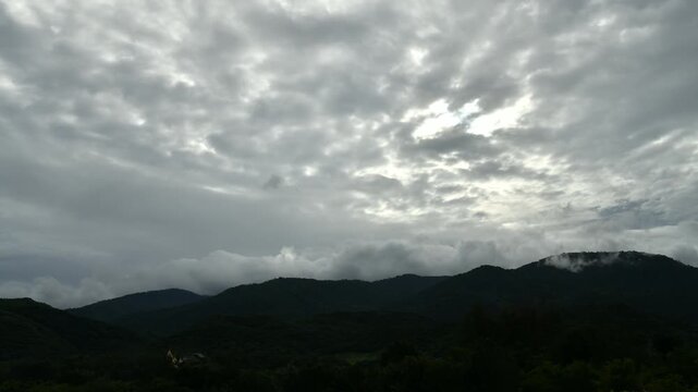 Dramatic cloud timelapse with dense white fog and mist rolling over a lush green mountain forest. Time-lapse footage.
