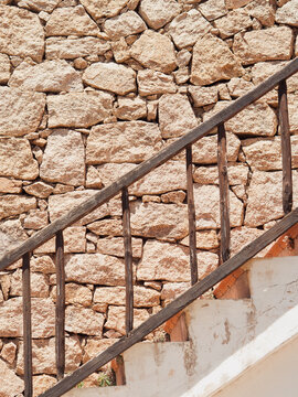 Rustic wooden staircase railing against a granite dry stone wall in Porto Cervo, Sardinia