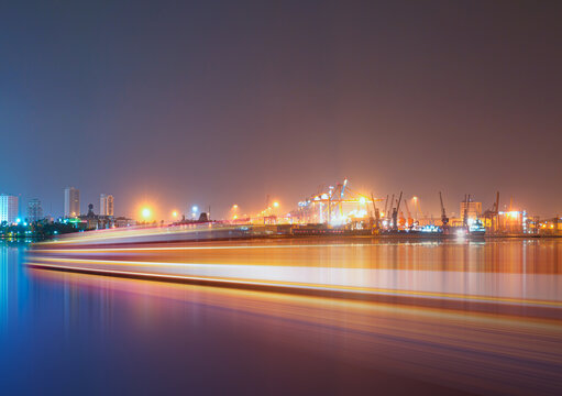 Long exposure photo of A large ship approaches the port at night to unload its cargo