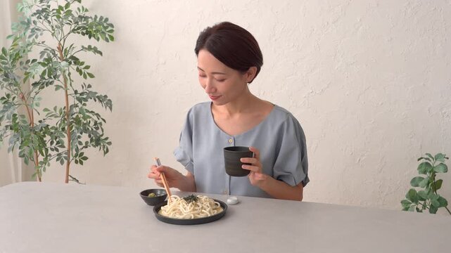 リビングでざるうどんを食べる女性