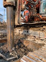 Fototapeta premium Heavy-duty drilling rig machinery operating at a construction site, digging deep into the muddy ground