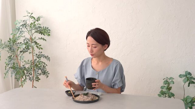 リビングでざるそばを食べる女性