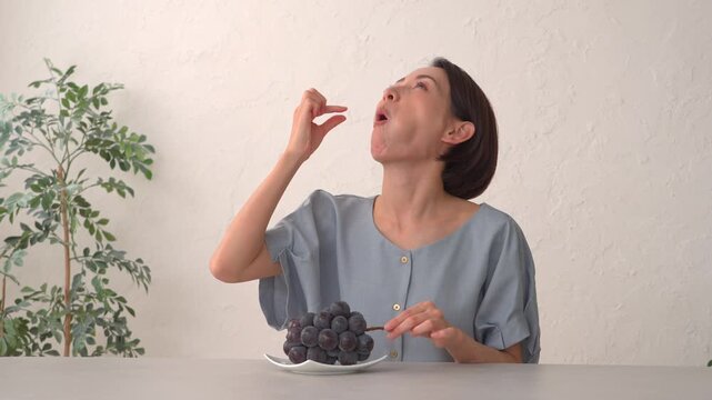 リビングでぶどうを食べる女性