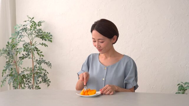 リビングで柿を食べる女性