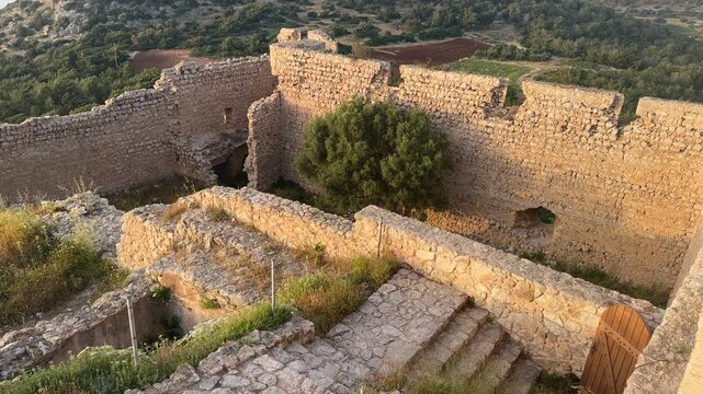 Handheld pan up and left shot of historic Kritinia Castle with a dramatic sunset over the sea in Rhodes Greece