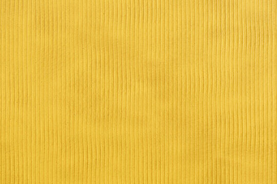 Superficie gialla con righe verticali regolari e texture corrugata. Immagine minimalista e geometrica, ideale per sfondi, packaging, design contemporaneo e progetti grafici.