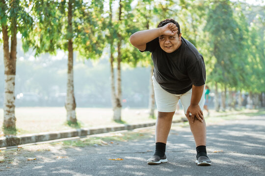 asian fat man slouching tired during his morning jog alone in the park