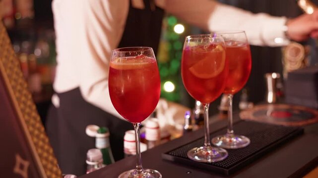 Red cocktail glasses on bar counter with blurred people and warm party lighting