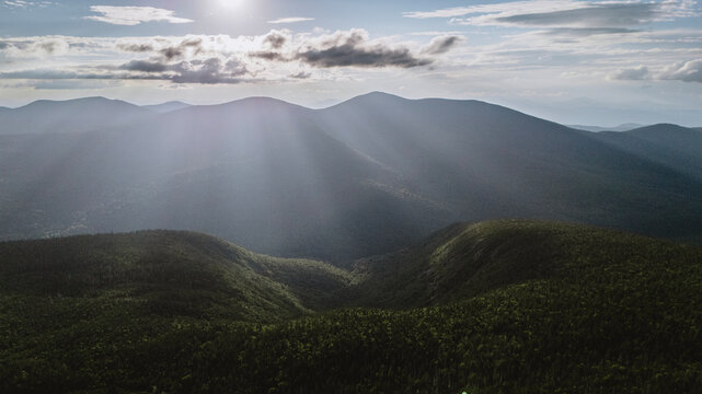 Sunlight streams over layers of forested mountains, Maine