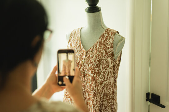 Business owner photographs dress on mannequin at home for reselling