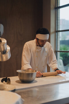 A young professional chef prepares fresh dough in a kitchen
