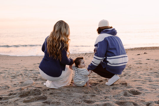 Young family of three watching a beach sunset