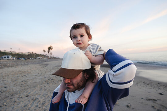 Man carrying cute toddler on his shoulders at beach