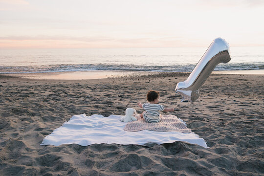 Baby celebrating first birthday on the beach at sunset